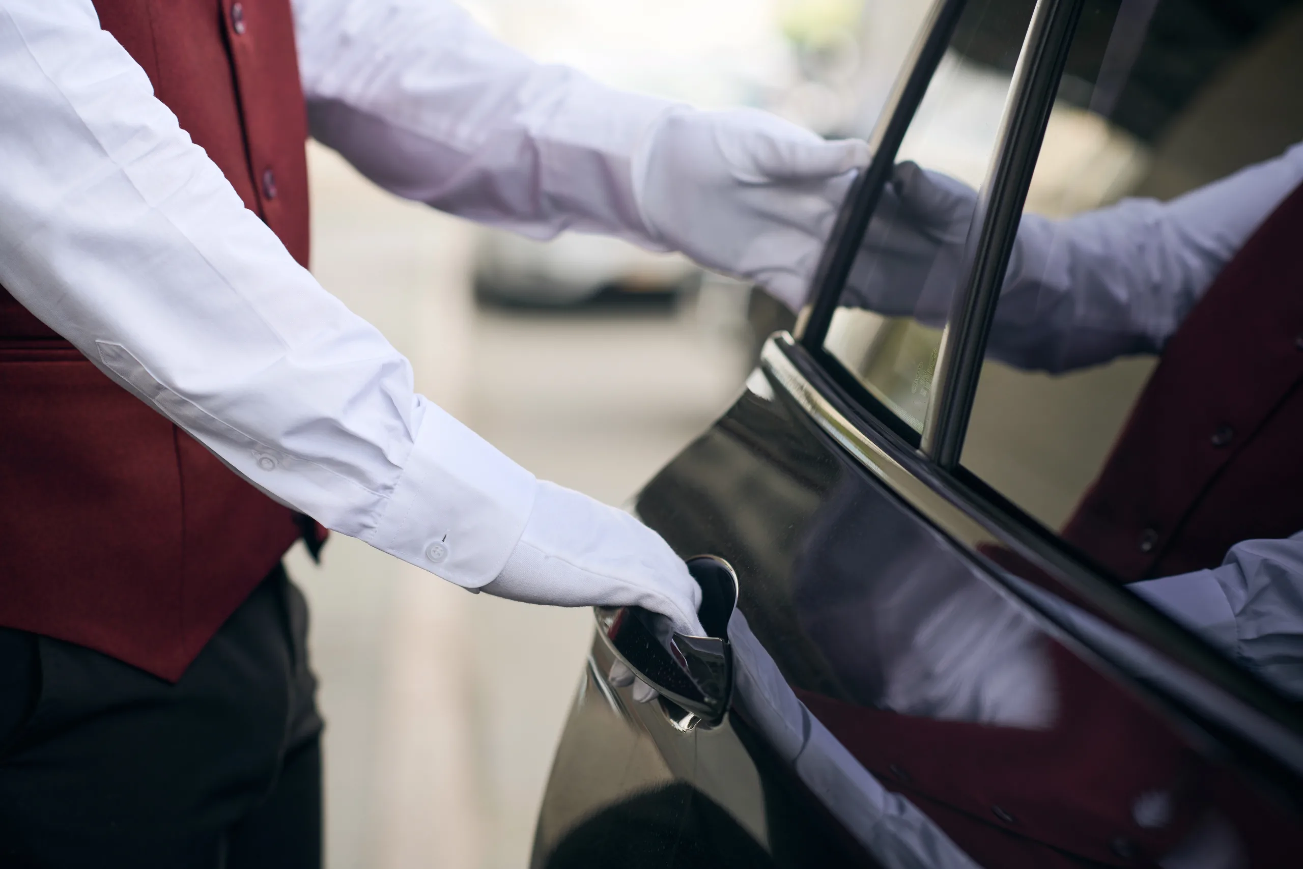 A professional chauffeur opening the door of an executive car